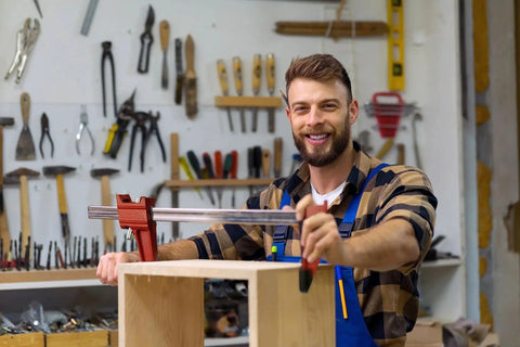 Man using Beefed Up 12 Inch Bar Clamp Set For Woodworking And Metalworking Four Pack With Quick Release Steel F Clamps 600 Pound Load Capacity Built To Hold Glue Adhesive Bonding Nails Or Screws Welding And Bolting DIY Projects By HimaPro in a workshop