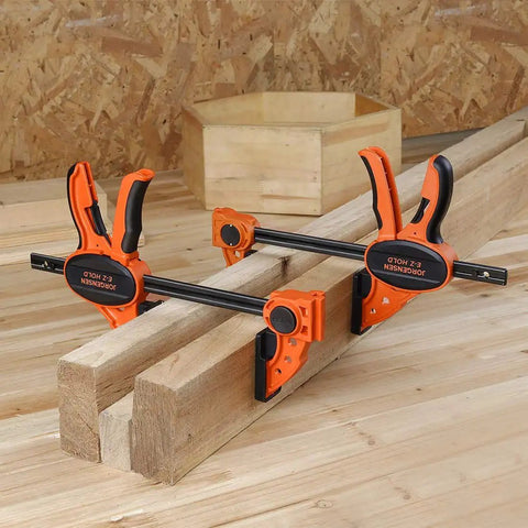 Two Pack Six Inch One Hand Clamp And Spreader Set With 300 Lb Clamping Force holding wooden planks on a workbench