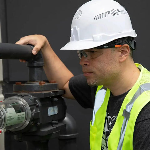 Man wearing Low Profile Safety Glasses Narrow Lens Z87 1 Anti Fog Scratch Resistant 2 Pack, hard hat, and safety vest working with machinery.