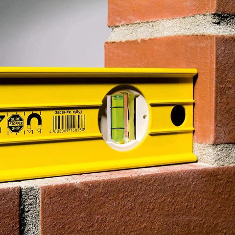 Stabila 37424 24 Inch Builders Level With High Strength Box Frame for framing tile and trim work, bright vials visible on brick wall