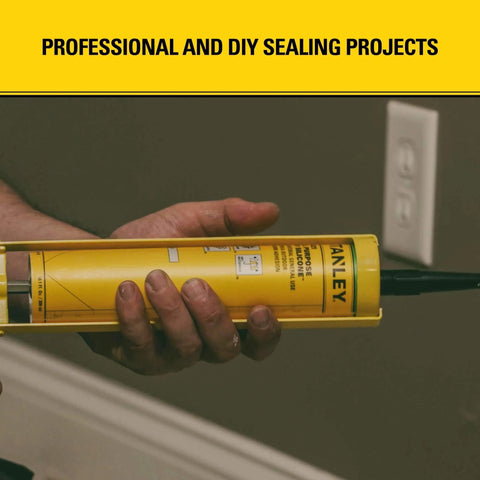 Person holding yellow caulk gun cartridge, labeled for professional and DIY sealing projects, near a wall outlet.