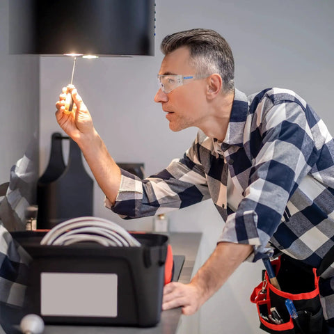 Man wearing ANSI Z87 Safety Glasses With Impact-Resistant Lenses And UV Protection 12-Pack while working on electrical task indoors.
